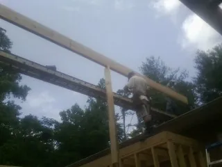 Carpenter setting a ridge beam over a new addition frame — Ice Dam Removal by Roofing Brothers in Mc Arthur