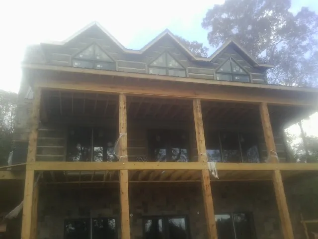 Dormers and porch framing on a large log home under construction — Roof Coating work by our crew in Mc Arthur
