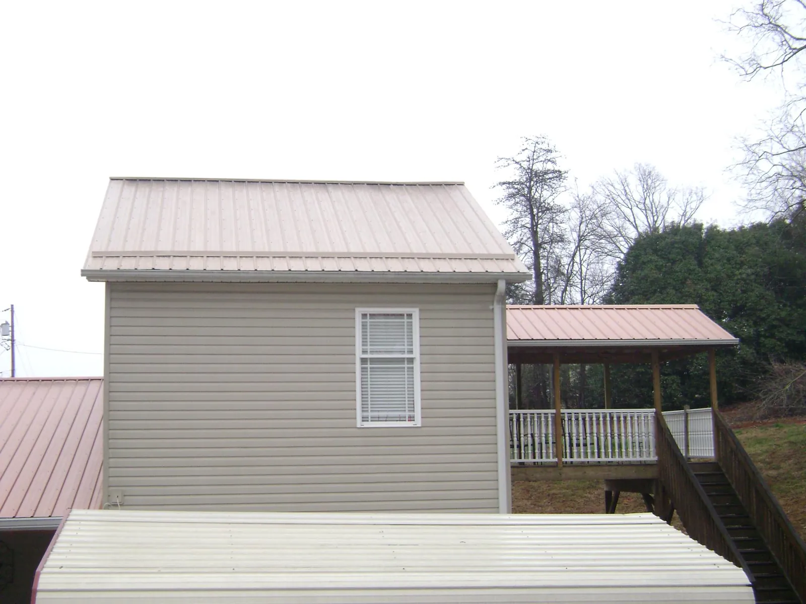Tan metal roofs on a two story addition and attached porch, from a Roof Replacement job in Mc Arthur