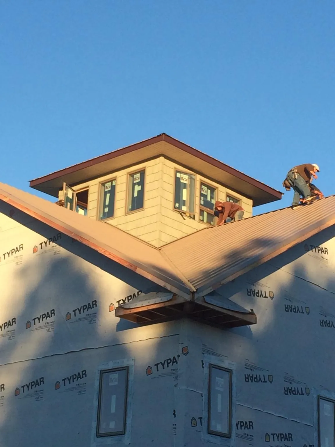 Roofers working around a rooftop cupola on a new metal roof at sunset — Roof Waterproofing in Mc Arthur by Roofing Brothers